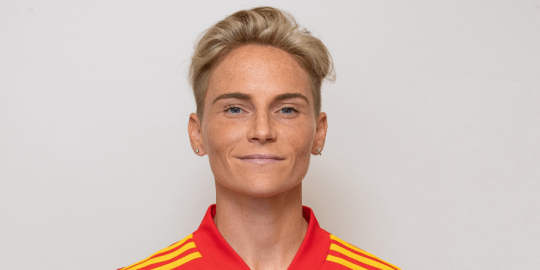 Jess Fishlock standing against a blank wall and smiling