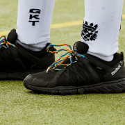Sports person wears Rainbow Laces in black boots on a playing field